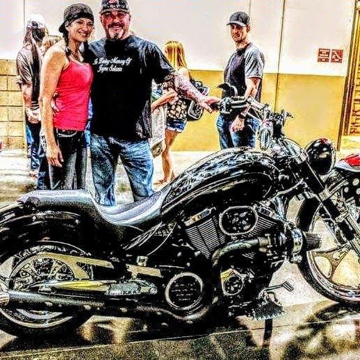 A man and woman standing next to a motorcycle.